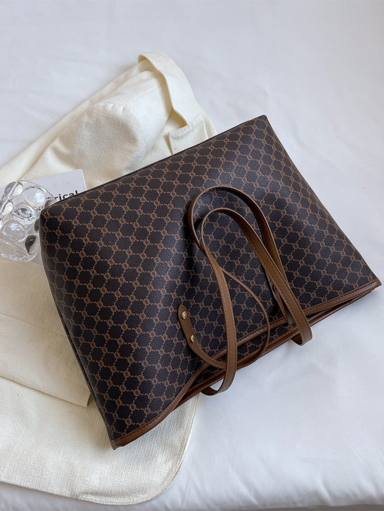 Bolso tote café para mujer sobre fondo blanco con detalle del acabado monograma