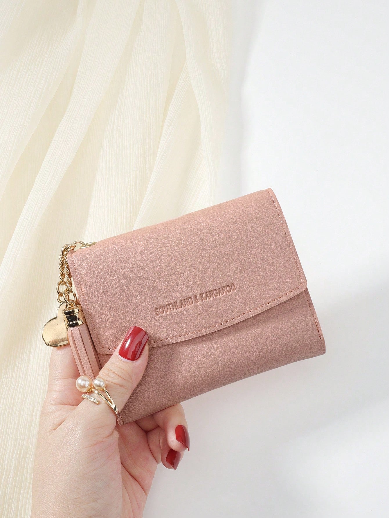 cartera rosa con borla decorativa
