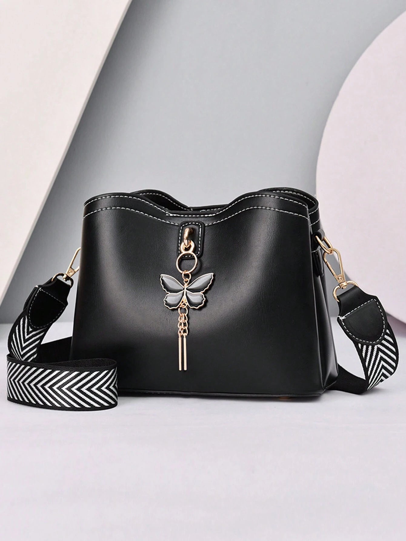 bolso negro crossbody para dama con mariposa metálica