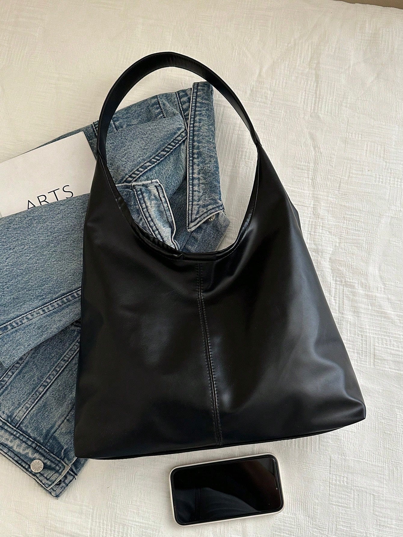 Bolso hobo negro para mujer junto a teléfono y prendas casuales
