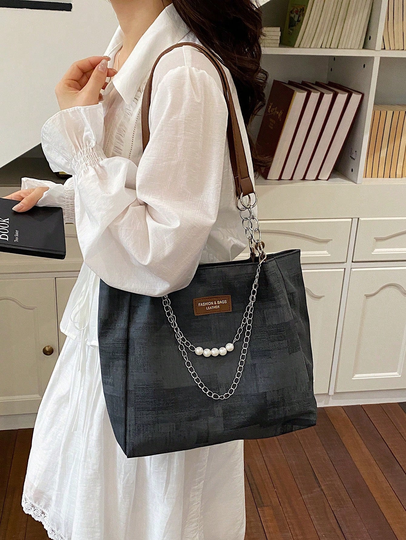 Bolso tote negro para mujer llevado al hombro con asas café