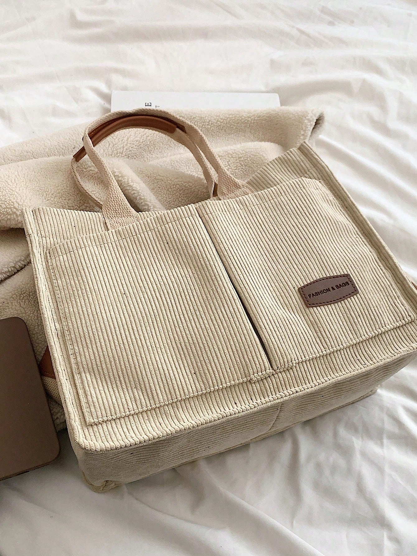 Bolso tote caqui para mujer vista superior sobre cama con textura de pana