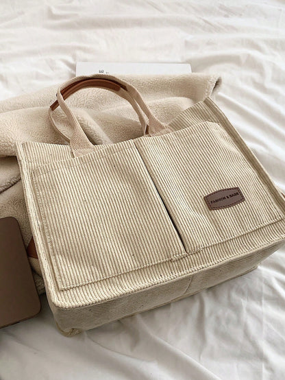 Bolso tote caqui para mujer vista superior sobre cama con textura de pana