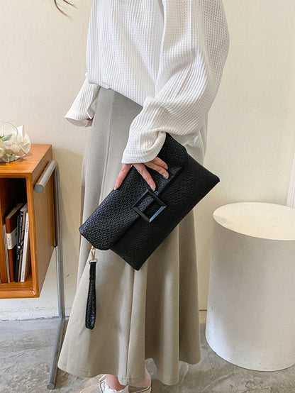 bolso clutch negro para mujer sostenido de mano con look elegante