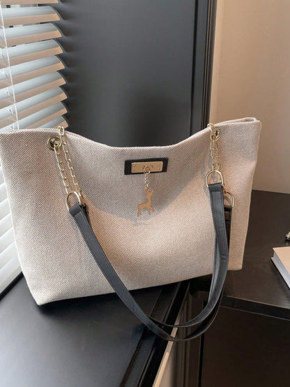 bolso beige tipo tote para dama sobre mesa con acabado texturizado