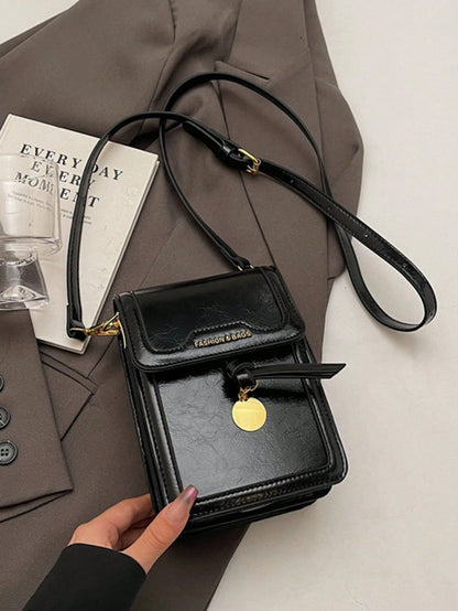 Bolso crossbody negro para mujer vista frontal sobre superficie clara